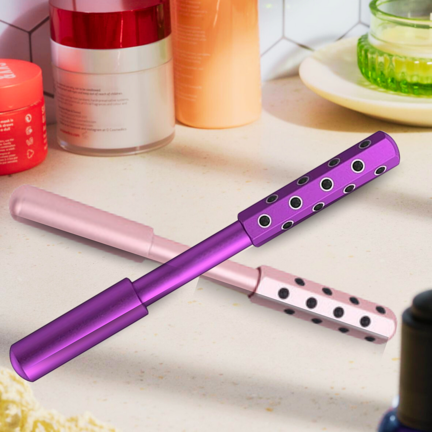Two germanium face rollers, one pink and one purple, crossed on a glossy white lacquered table, perfect for natural anti-aging facial massage and skin revitalization.