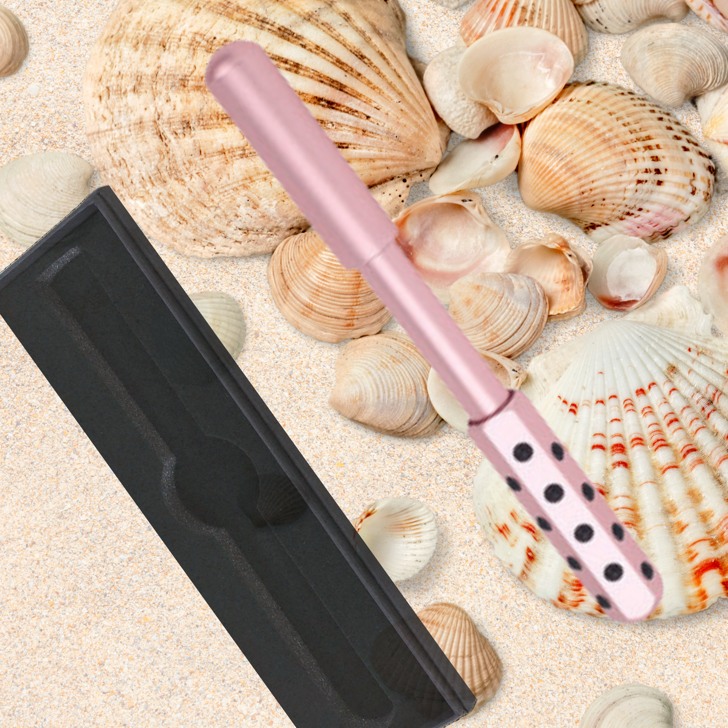 Pink germanium face roller with its storage case, displayed on sea shells, luxury facial massage tool